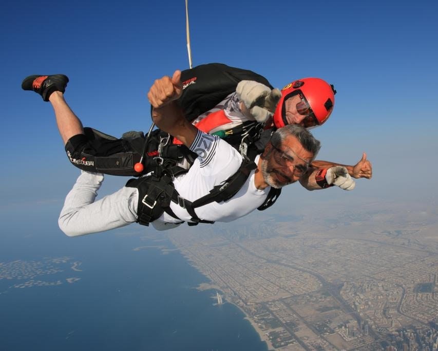 Umar Farooq Zahoor enjoying a tandem skydive, soaring above a stunning cityscape and coastline, showcasing a sense of adventure.