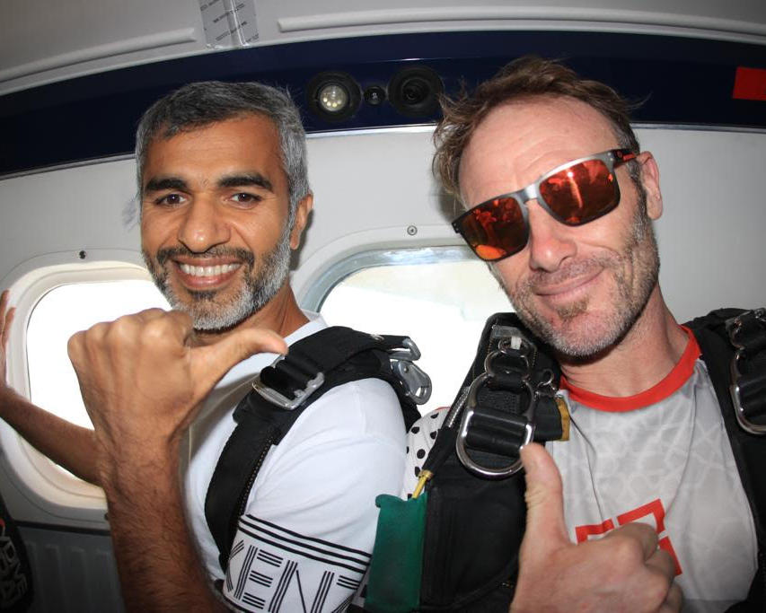 Umar Farooq Zahoor sharing a cheerful moment inside a plane with his skydiving partner, both smiling before their jump.